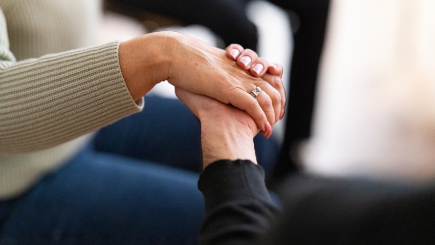 Cropped shot of people holding hands in a support group session. Close-up of people sitting together holding hands during mental health therapy meeting.